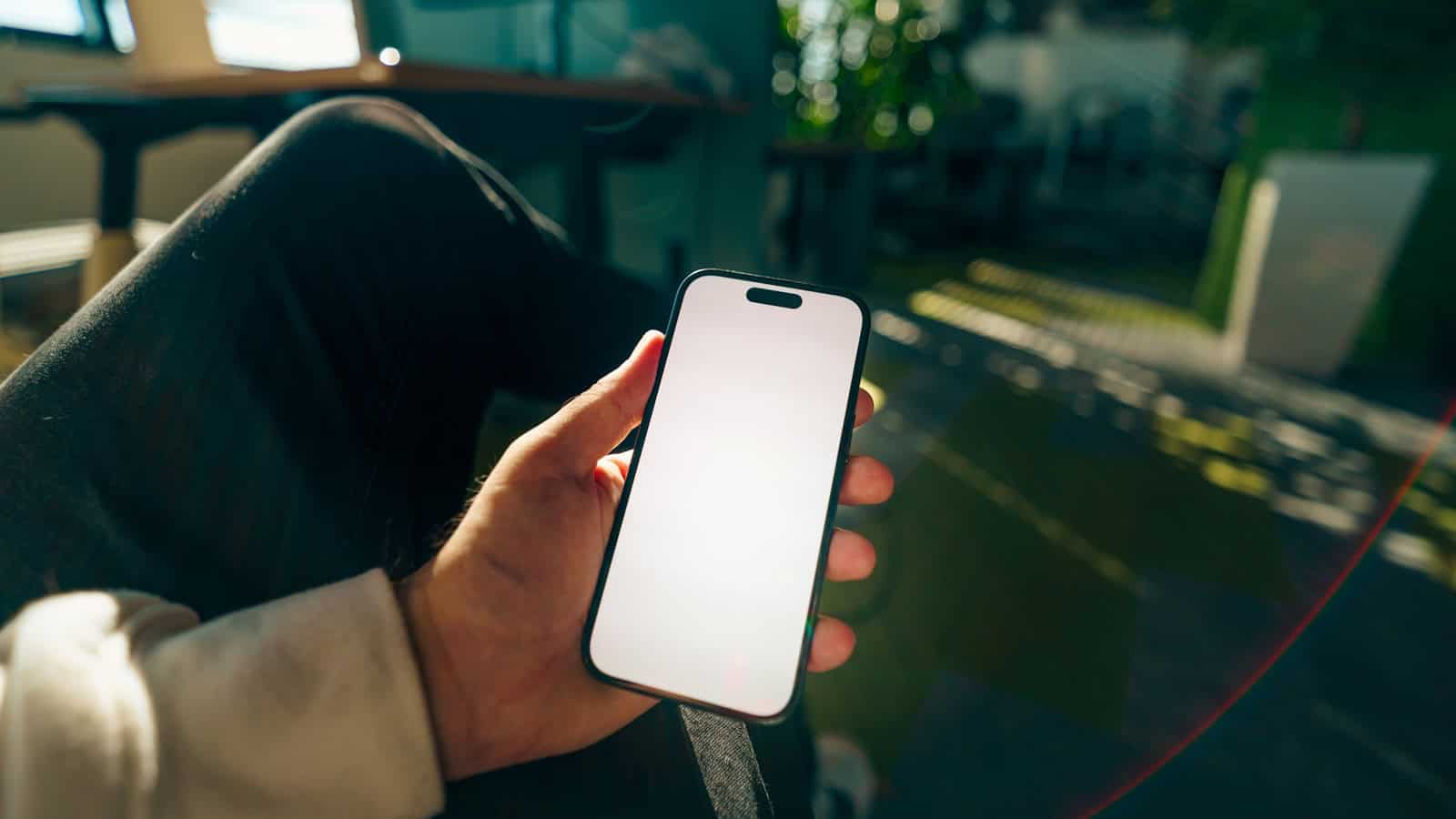 Hand holding a smartphone with a blank display