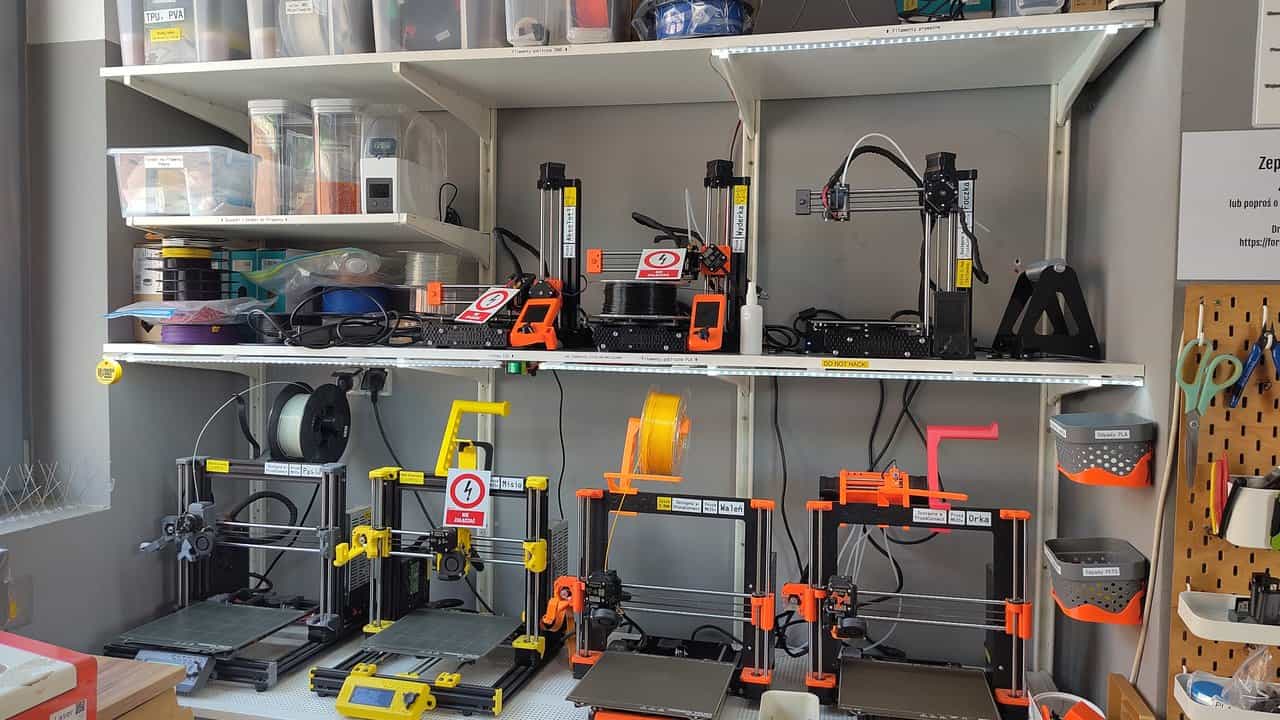 A makerspace shelf holding several consumer FDM 3D printers with spools of filament