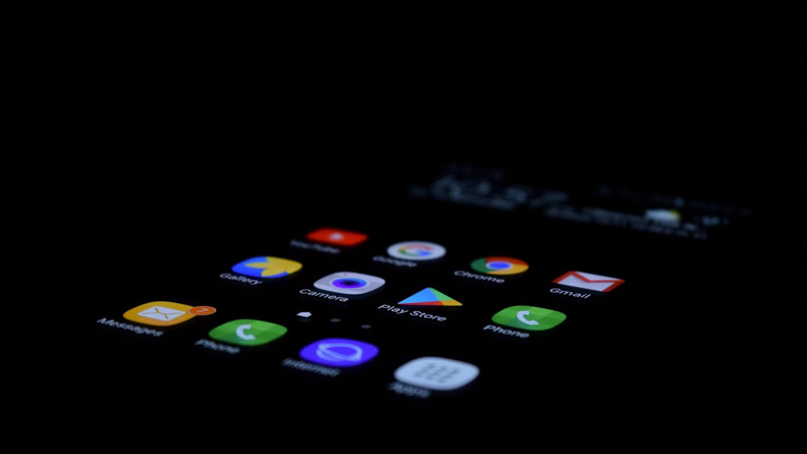 A close-up of app icons glowing on an Android phone screen in a dark room.