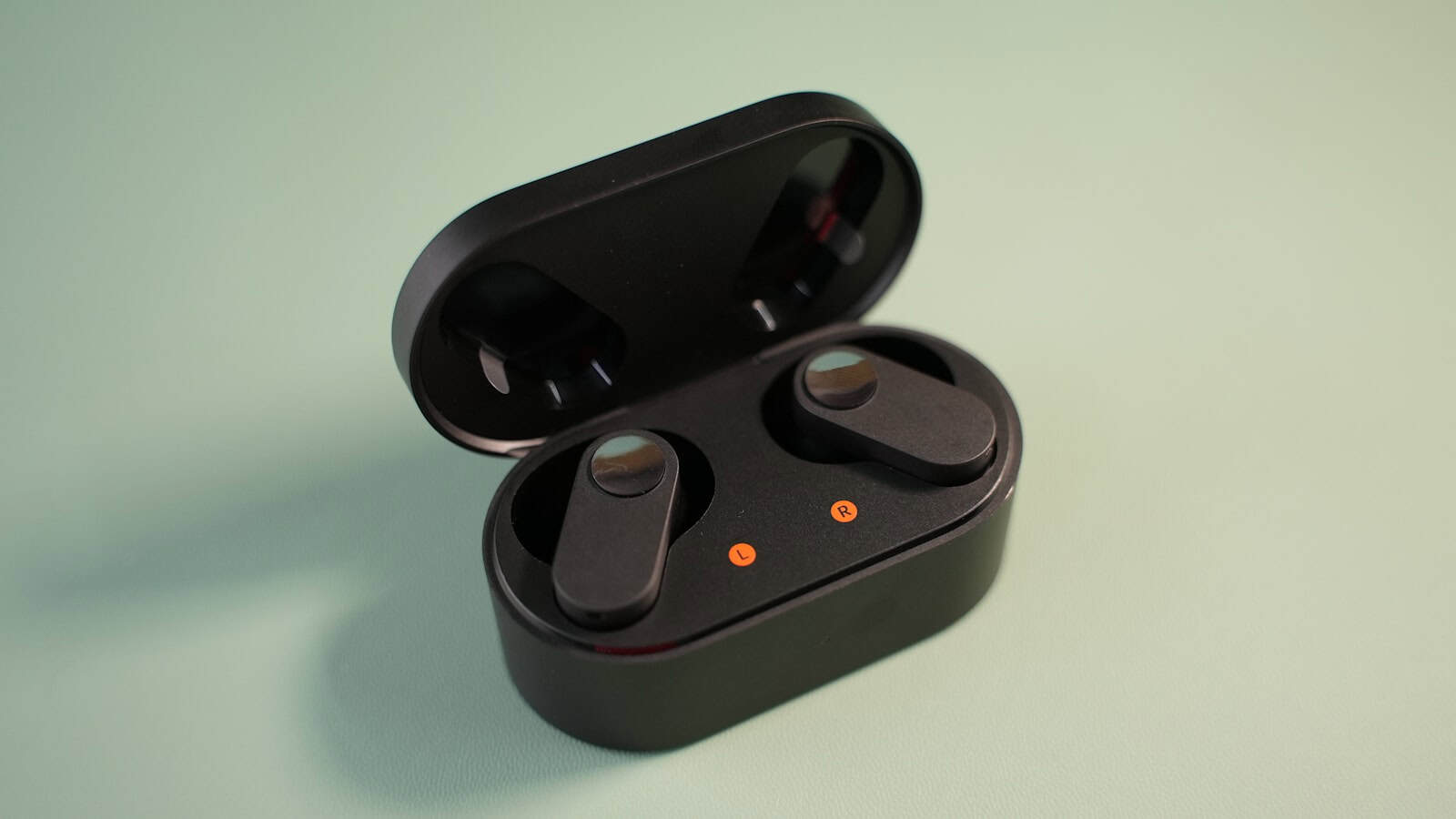 An open black wireless earbud charging case with both earbuds seated inside.