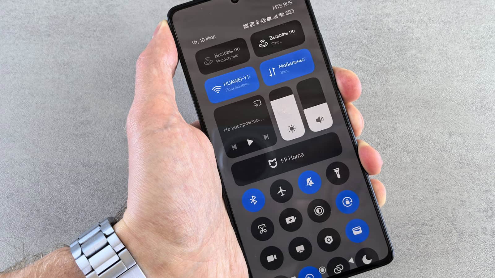 A hand holding an Android phone with the quick settings panel and its toggles pulled down.