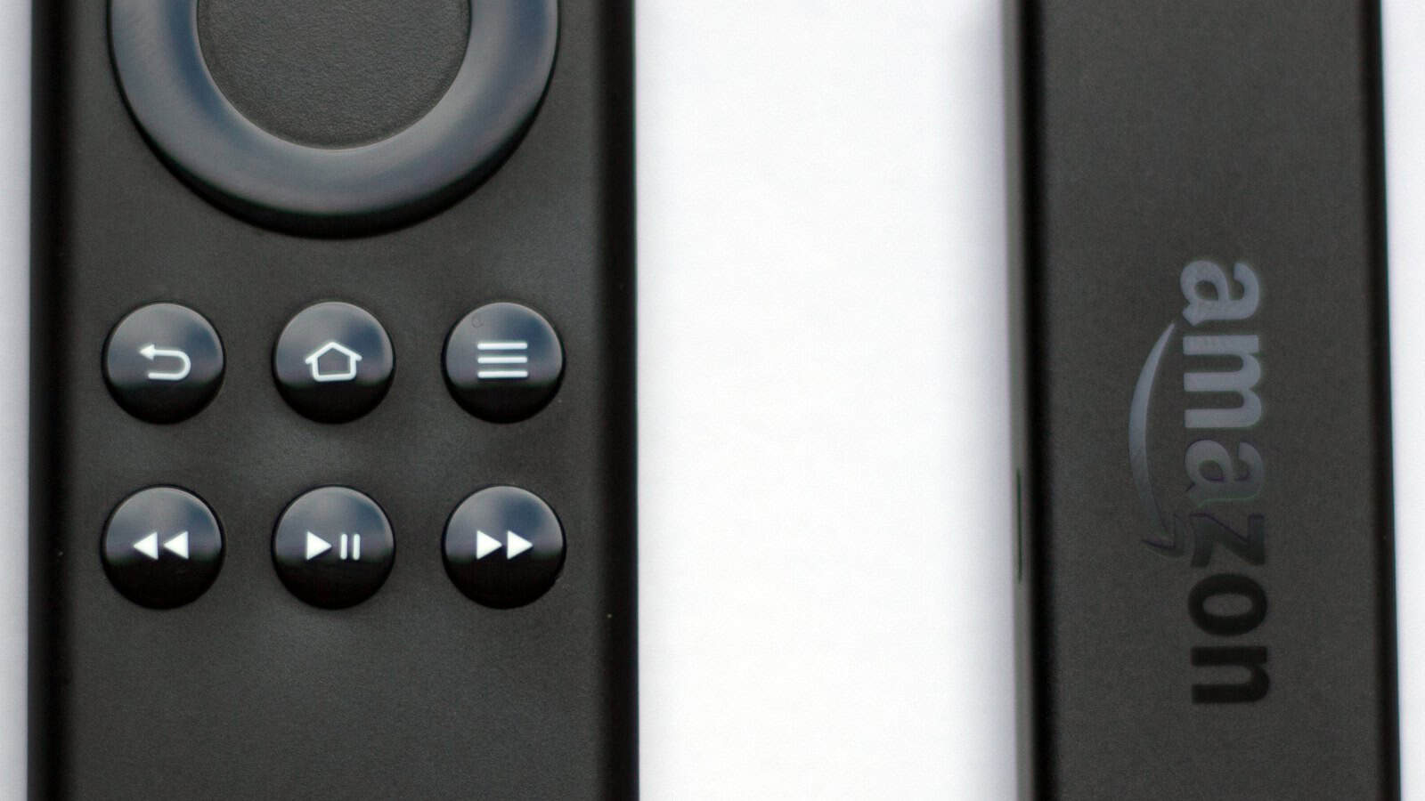 An Amazon Fire TV Stick and its remote showing the Back, Home, Menu, rewind, play and fast-forward buttons