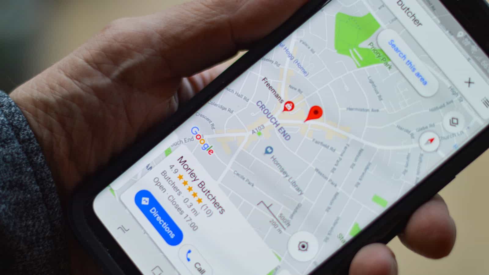 A hand holding a phone that is showing a Google Maps view with two red location pins.