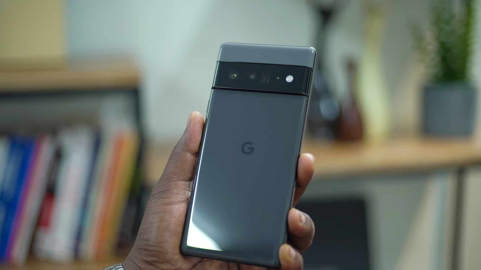 A hand holding a dark green Google Pixel phone with its camera bar facing the camera.