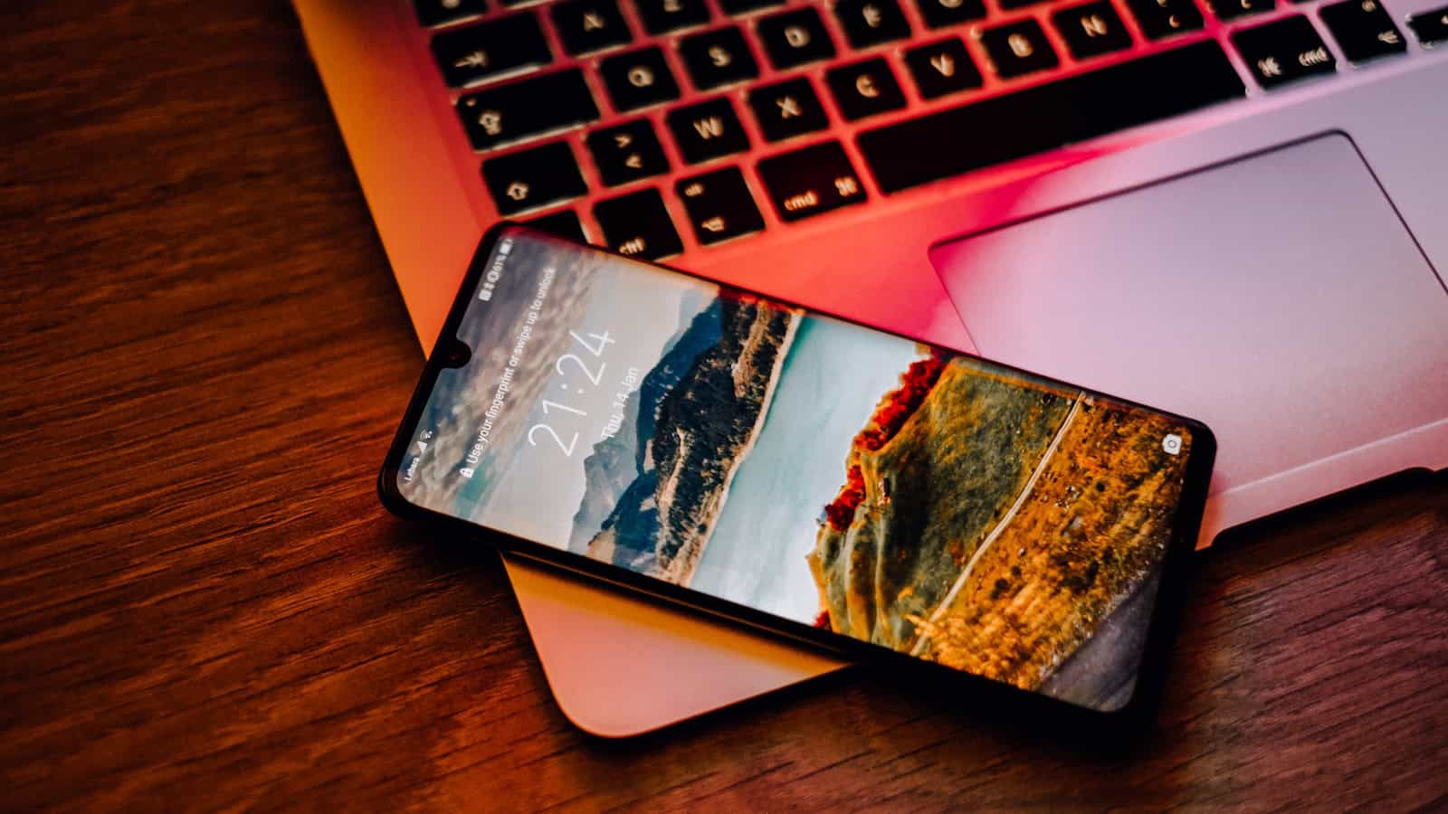 An Android phone resting on the wrist rest of an open laptop.