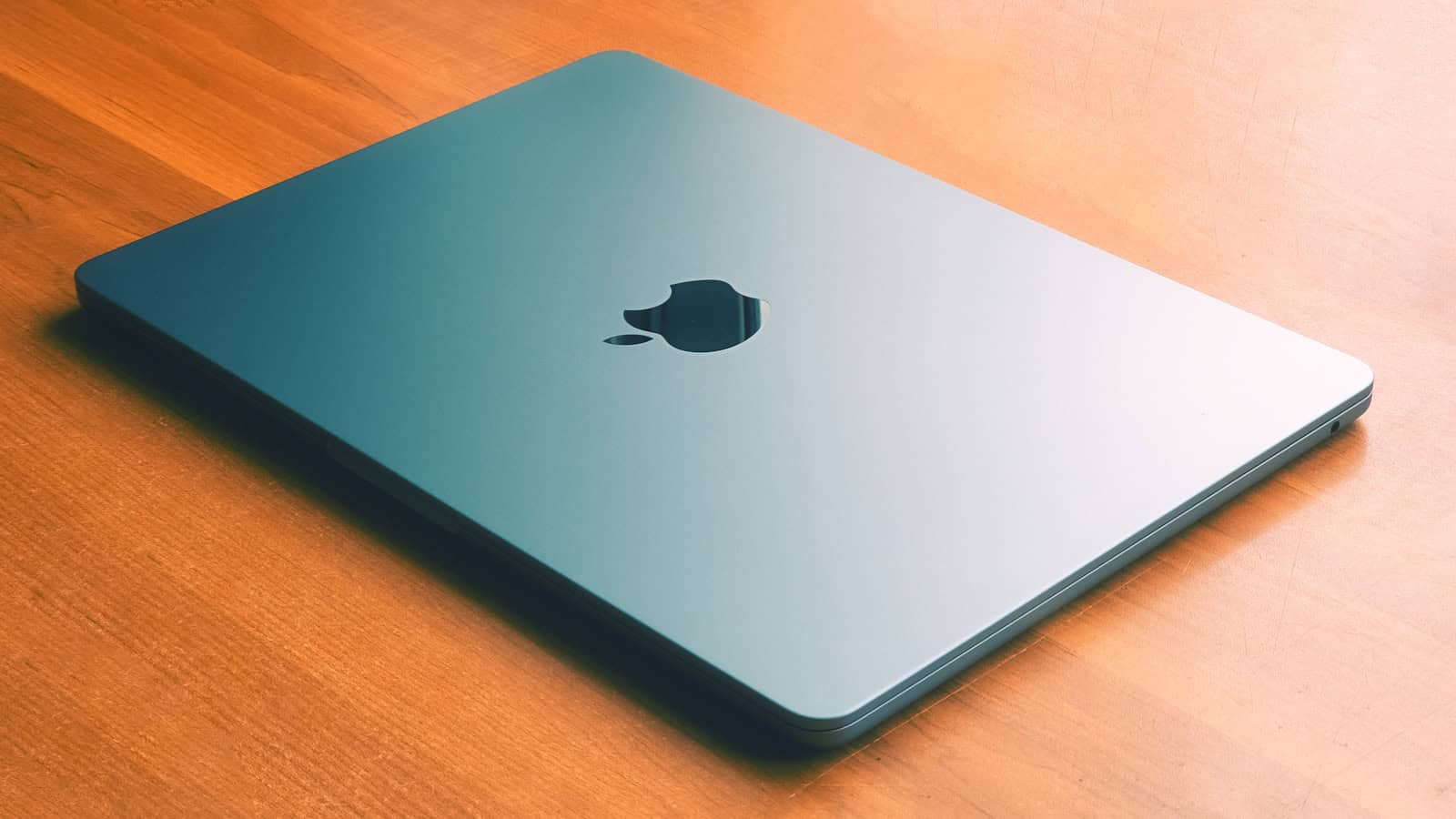 A closed MacBook on a wooden desk.