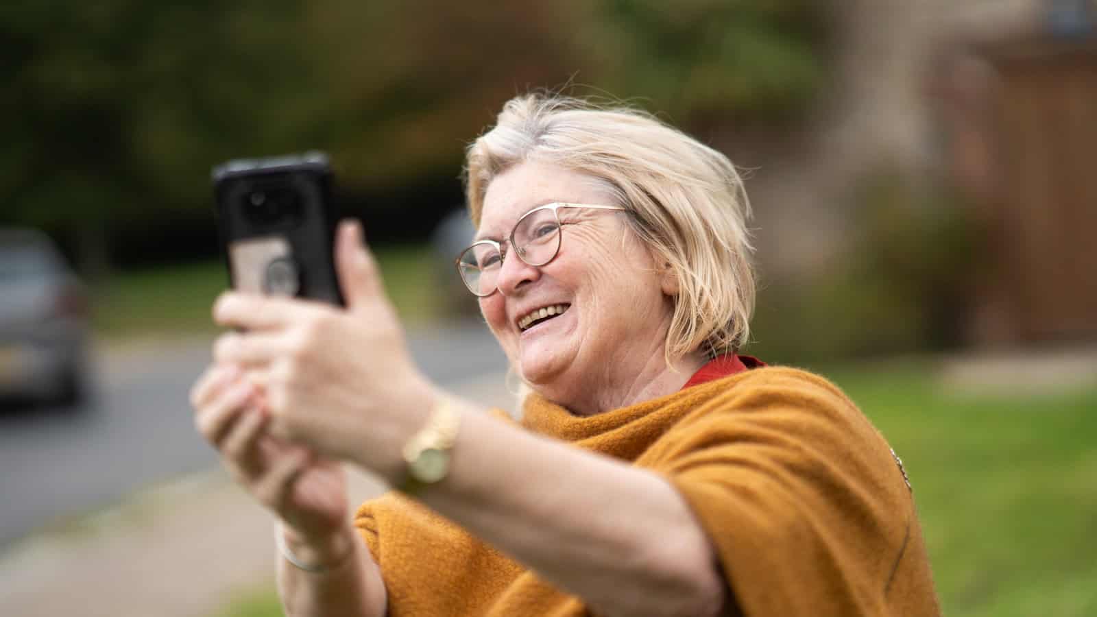 A woman holding a phone out at arm's length to read the screen.