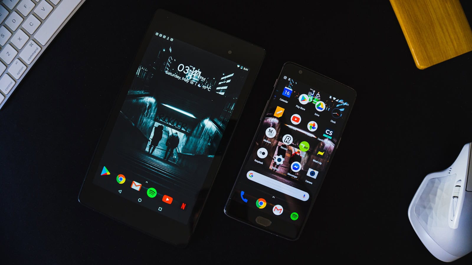 Two Android phones lying on a desk, one open at a folder of app icons.