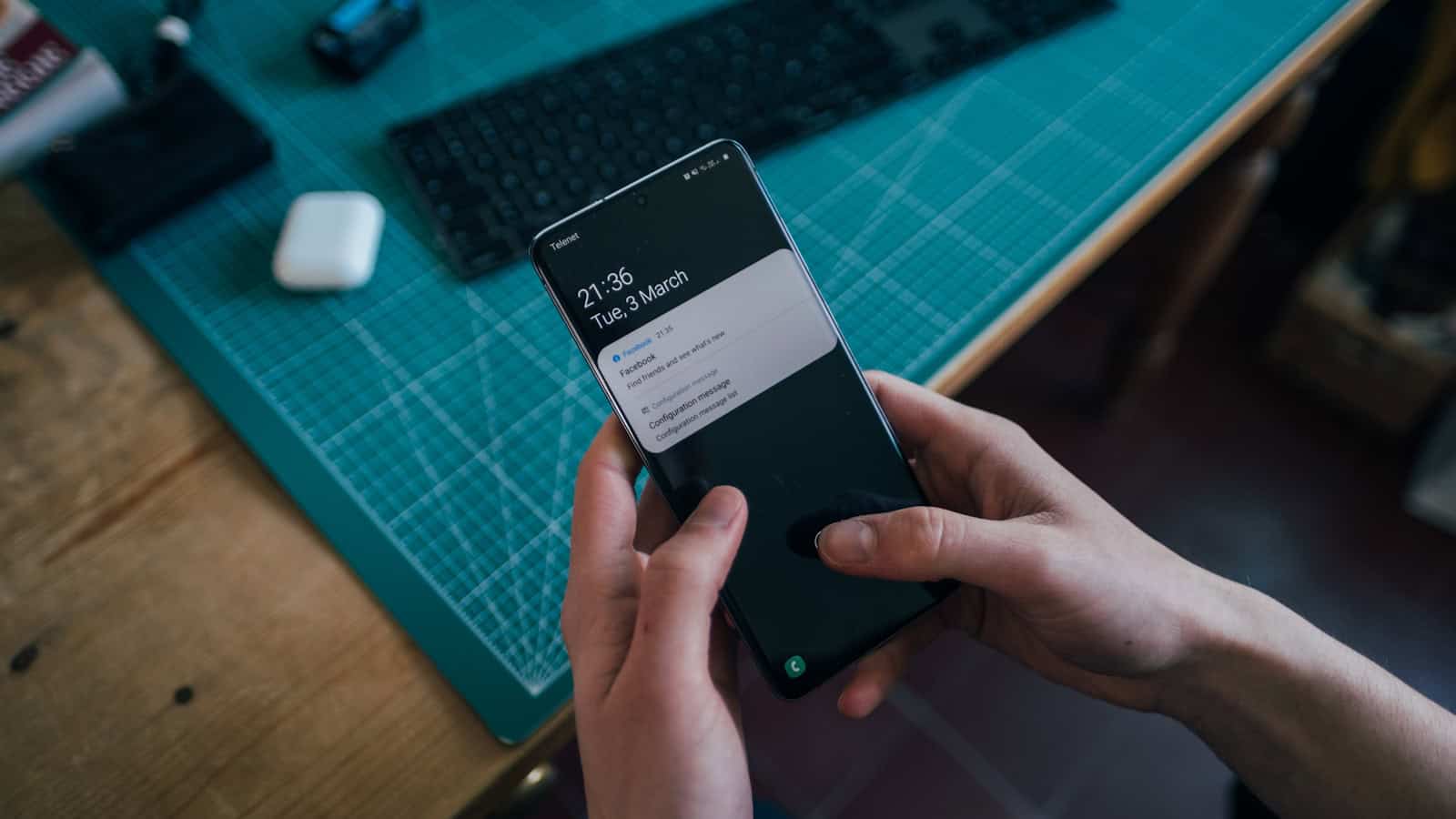 Two hands holding a black Samsung Galaxy phone showing a One UI screen.