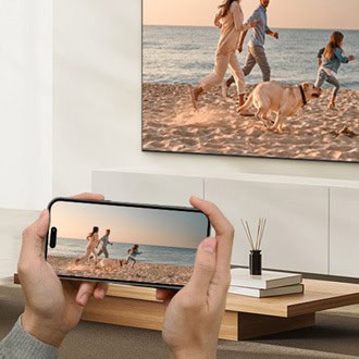 An iPhone mirroring a beach video to a wall-mounted Samsung TV over AirPlay