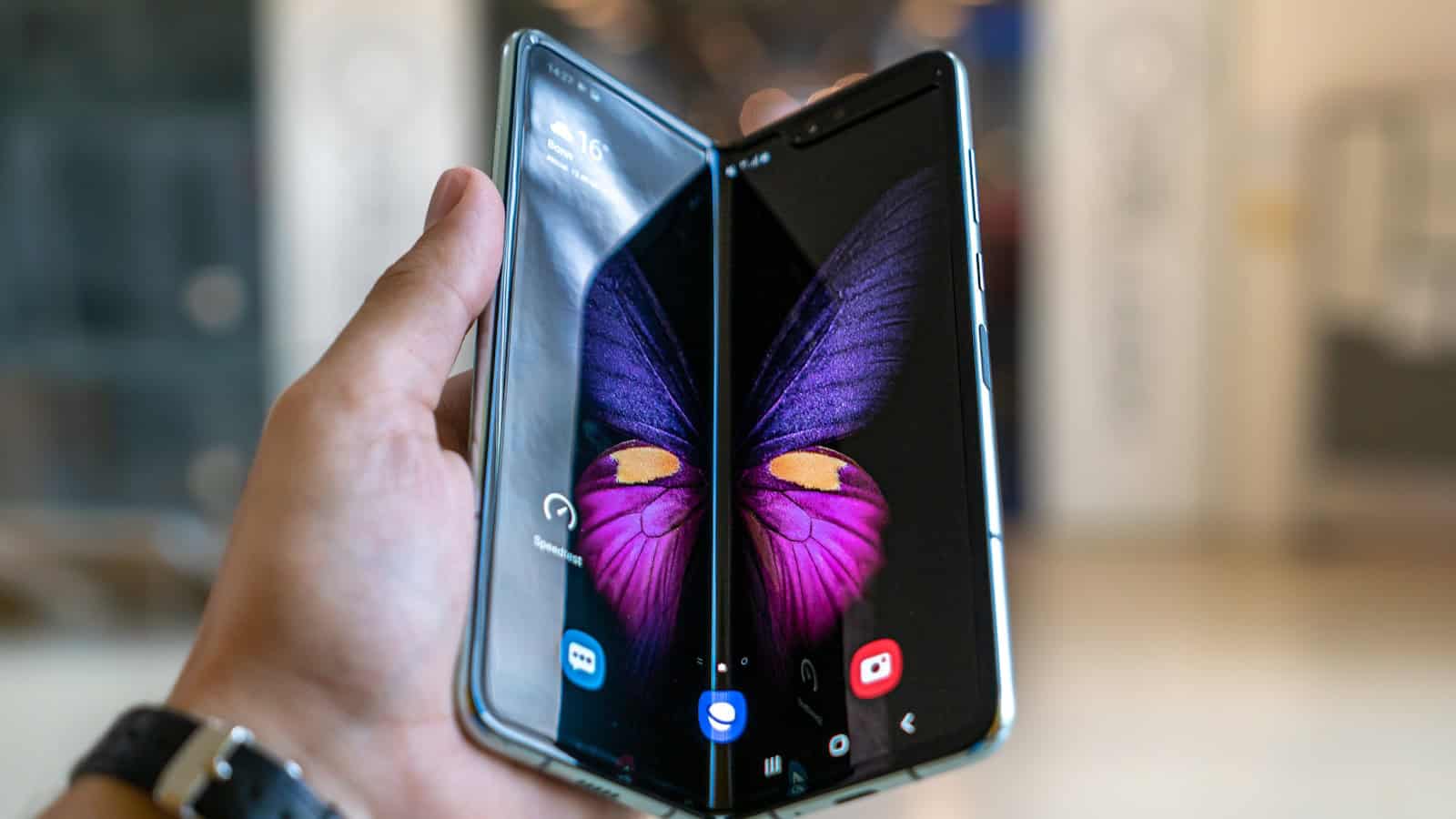 A Samsung foldable phone held half open in one hand showing its large inner display.