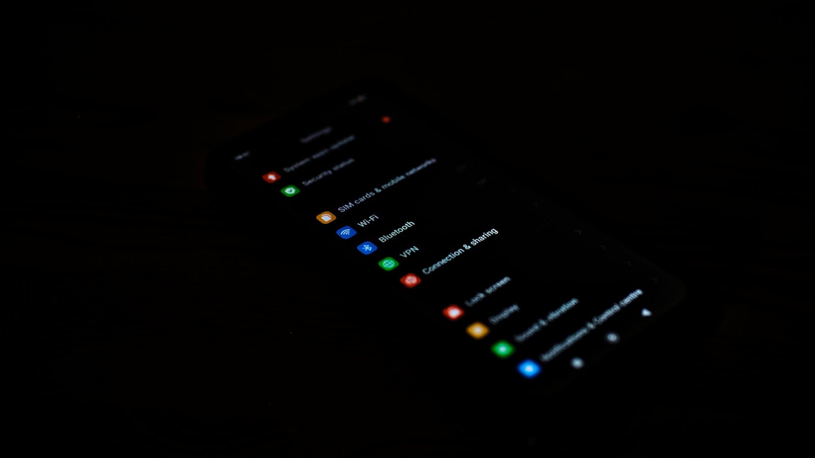 An Android settings menu shown in dark mode on a phone lying in a darkened room.
