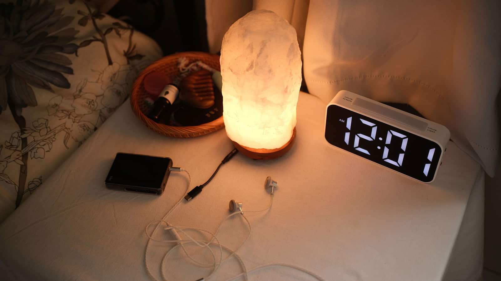 A bedside table at night with a phone lying face down beside a lit digital clock reading 12:01.