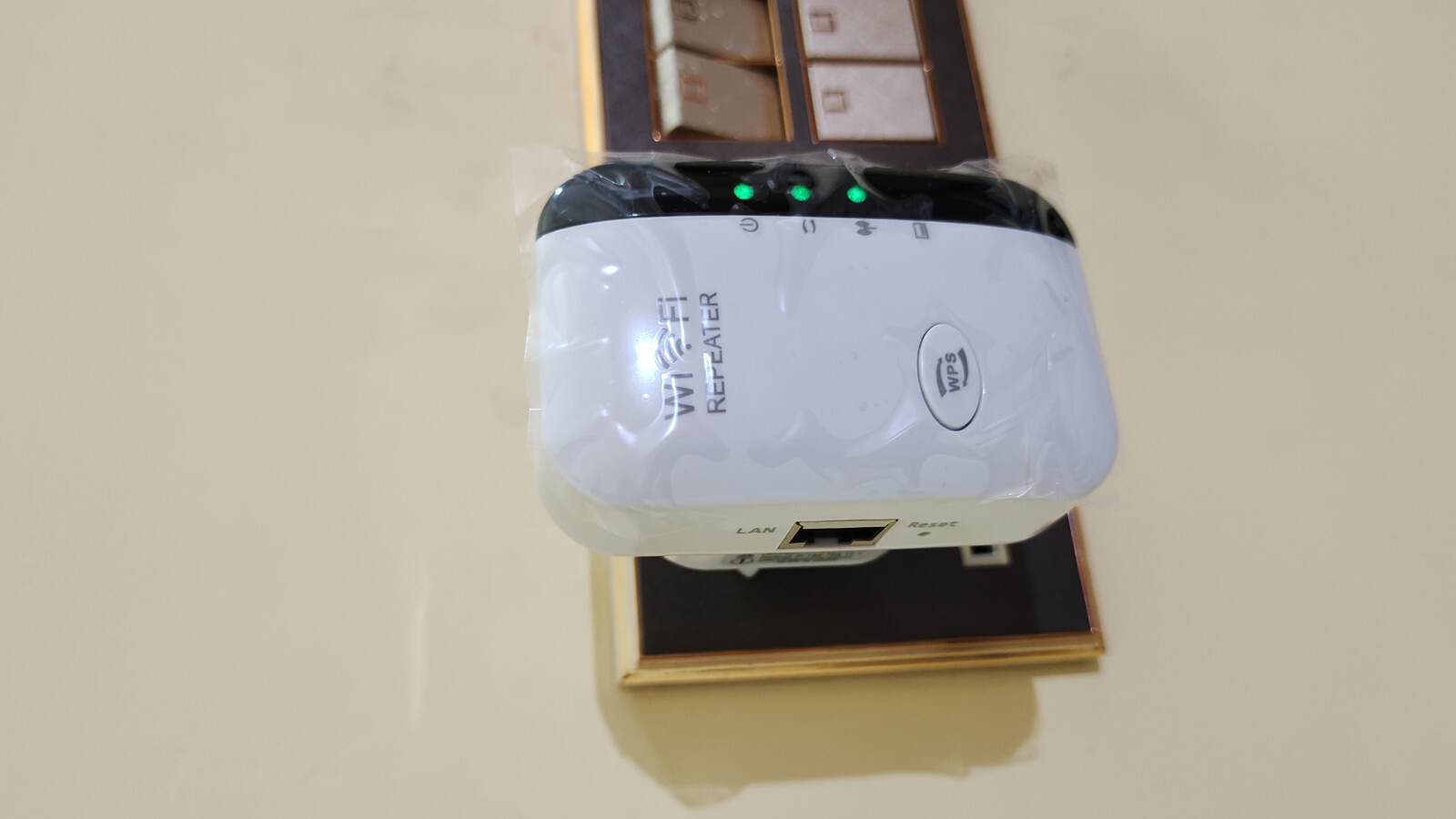 A white Wi-Fi range extender plugged into a wall outlet showing its status LEDs, WPS button and reset hole