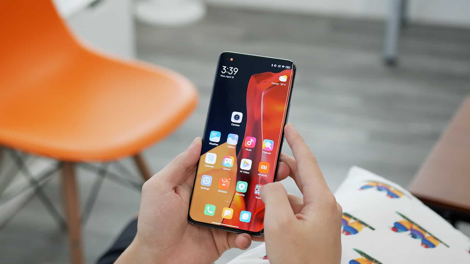 Two hands holding a Xiaomi phone open at a home screen full of colourful app icons.