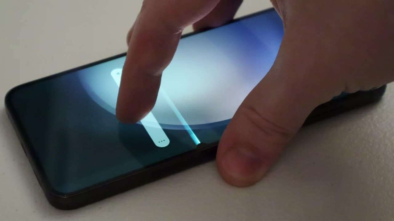A Samsung Galaxy S23 Plus lying on a desk with its lock screen showing a thin bright vertical line running through the display